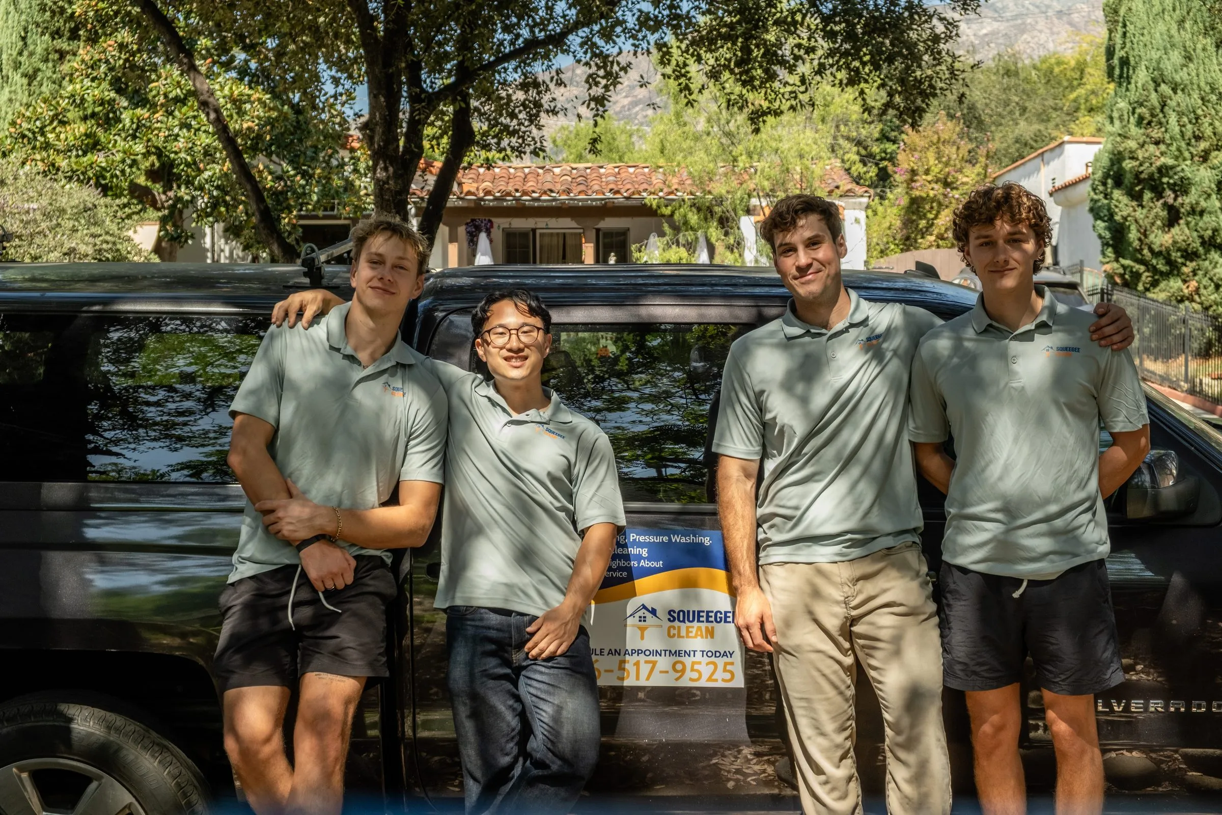Jordan, Wes, Elliott, and Jonathan of Squeegee Clean Windows in uniform polos beside the company truck