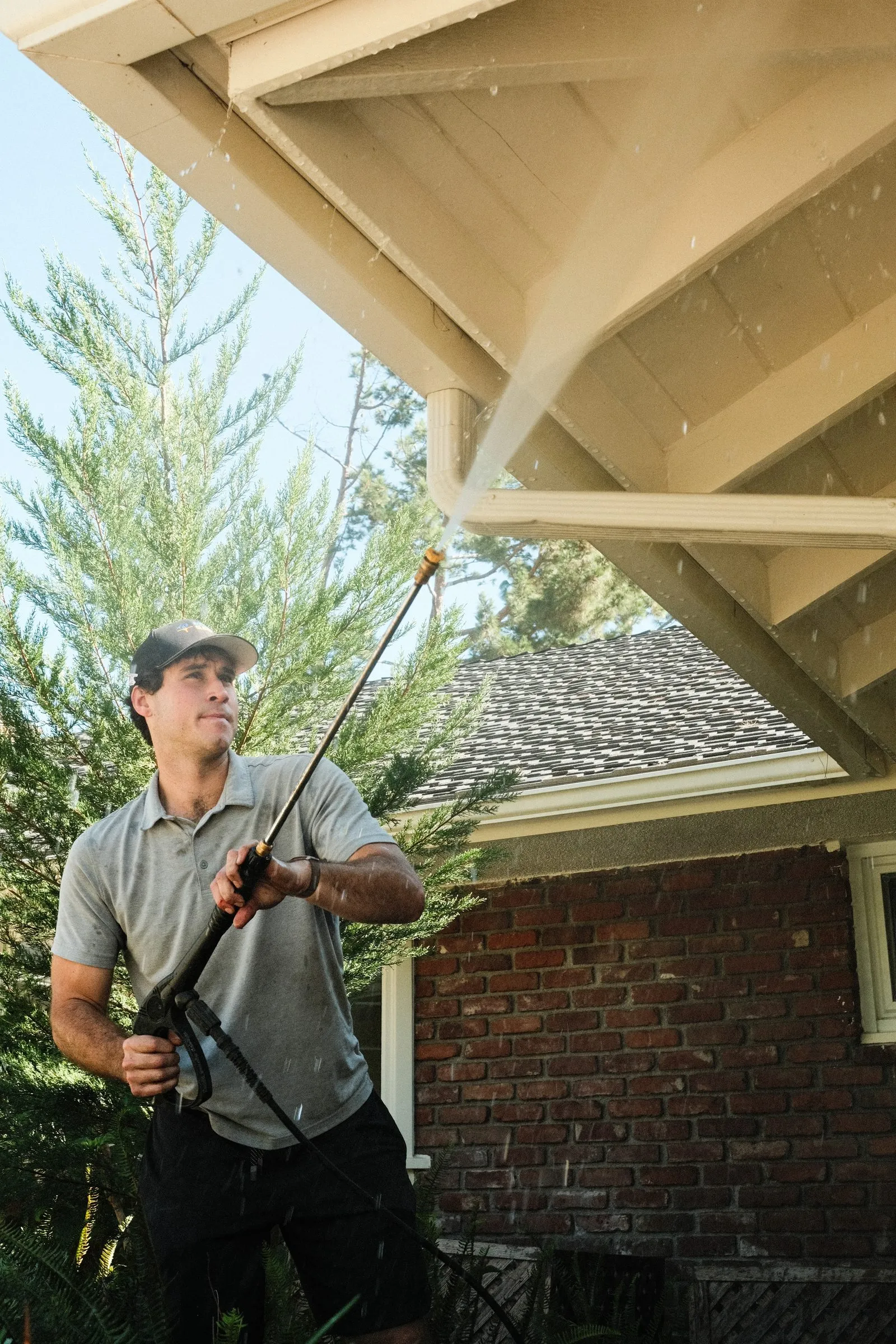 Elliot pressure washing the eaves of a brick house