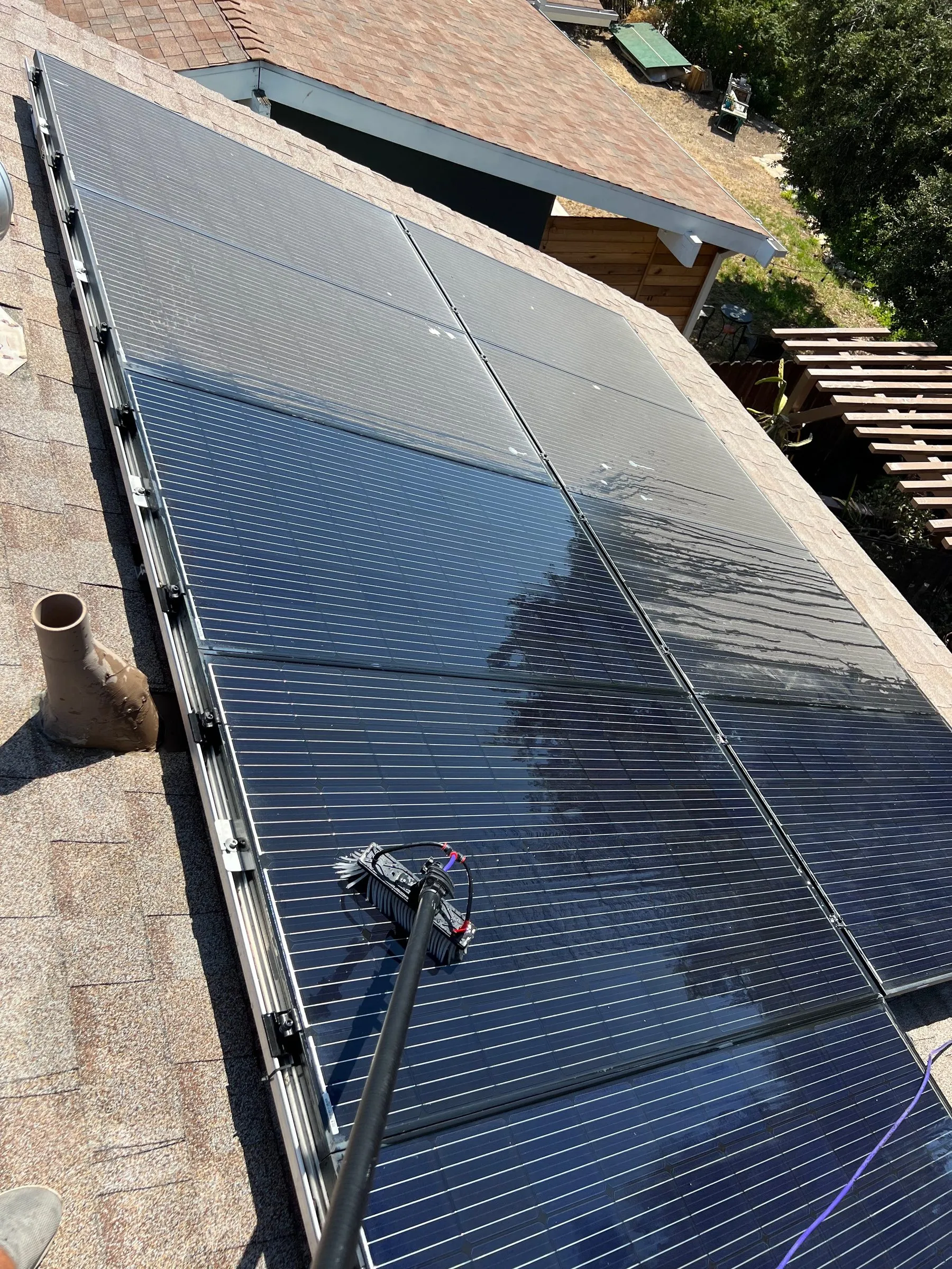 Rooftop solar array mid-clean with a sharp line between hazy and clean panels