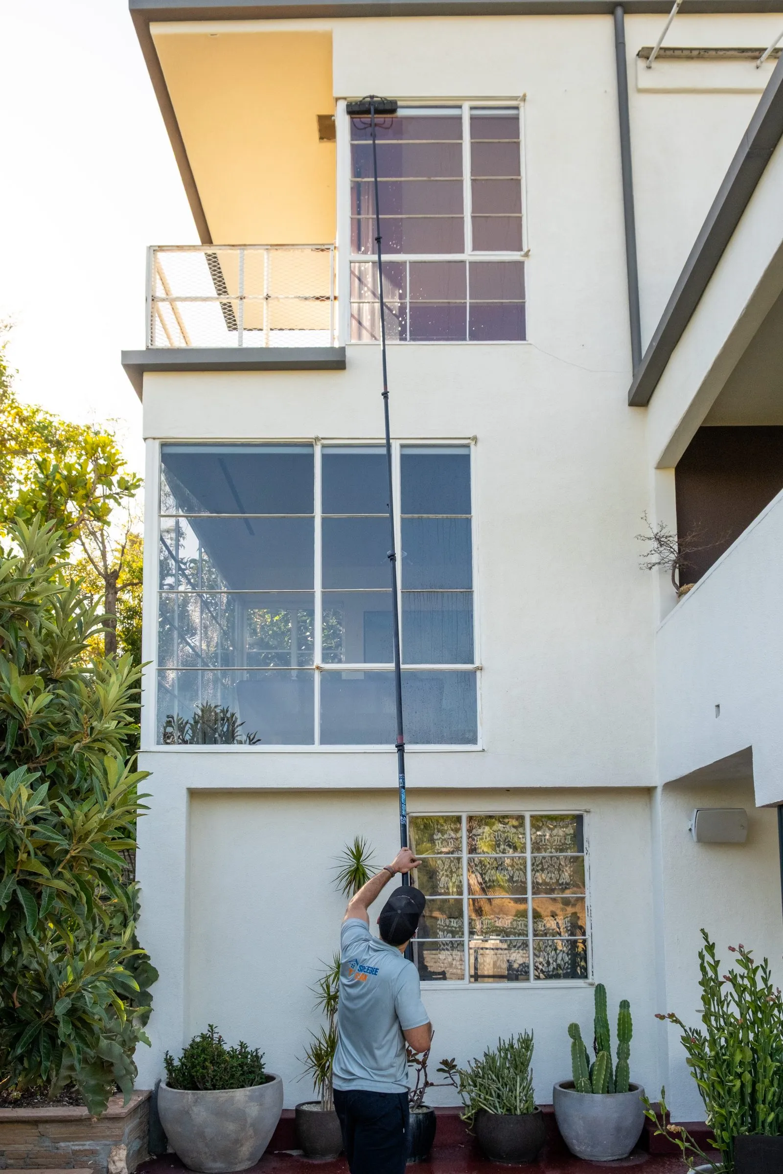 Water-fed pole reaching a second-story window on a white two-story house